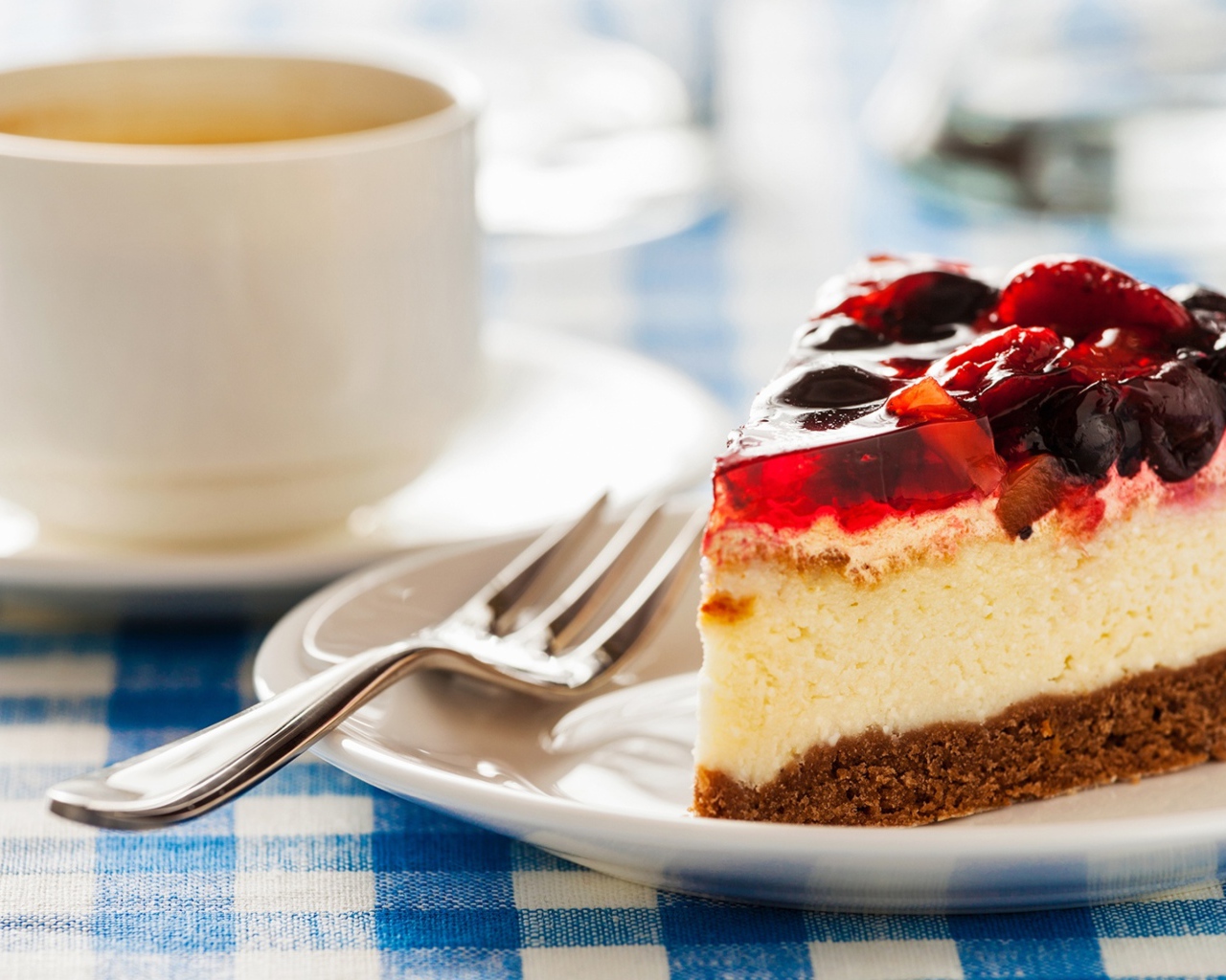 Кусок чизкейка с ягодами и желе на столе с чашкой кофе