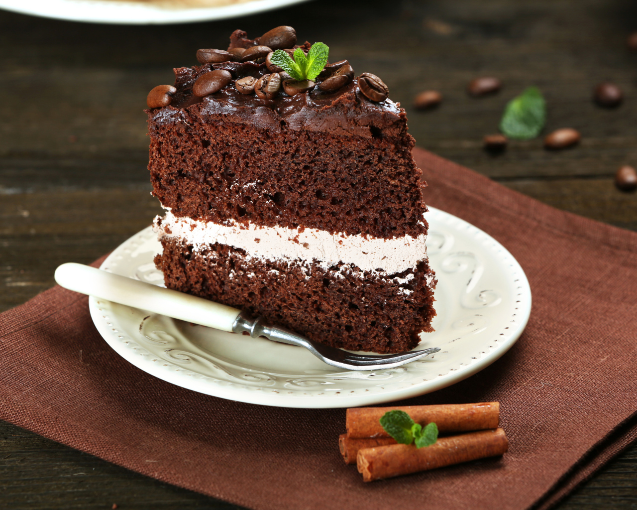 Кусок шоколадного торта с кремом и зернами кофе