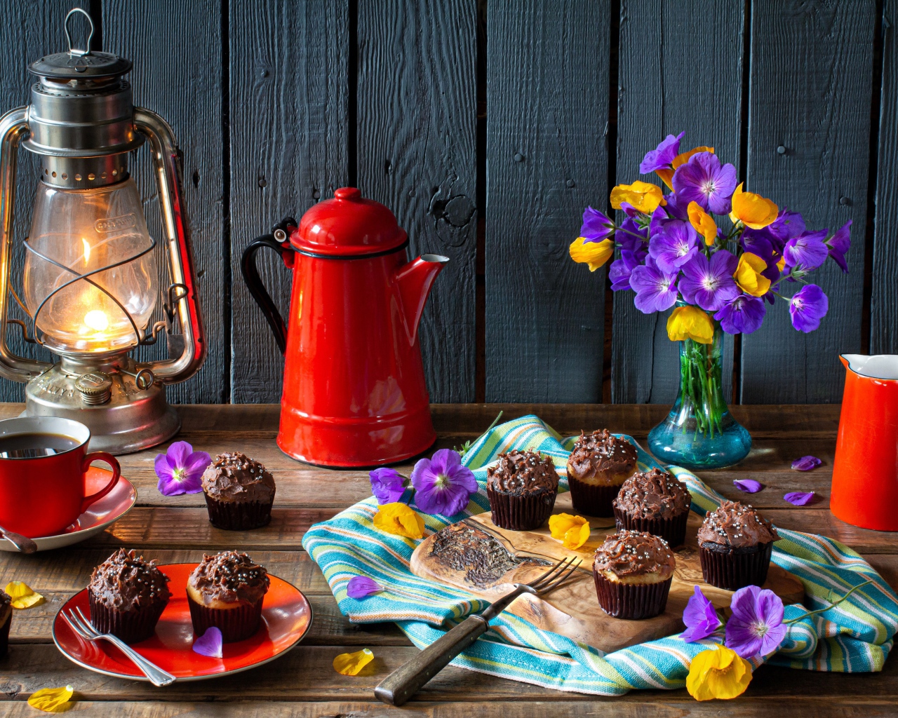 Аппетитные свежие кексы с кремом на столе с кофе, лампой и букетом цветов
