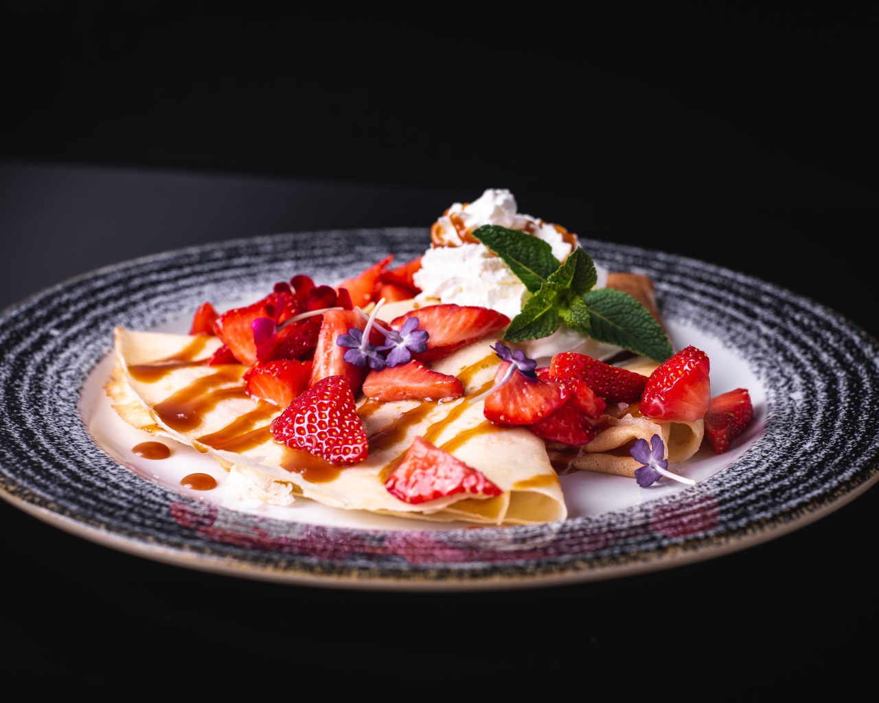 Аппетитные тонкие блинчики с клубникой на черном фоне