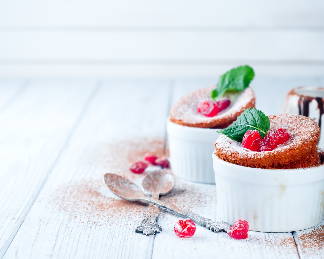 Пирожное с ягодами и сахарной пудрой на столе с ложками