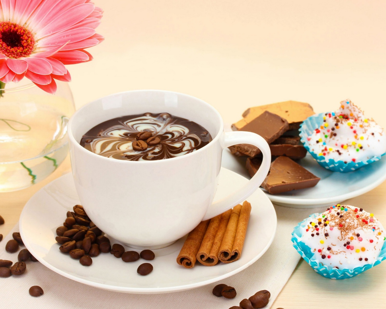 Конфеты на столе с кофе и герберой в вазе 