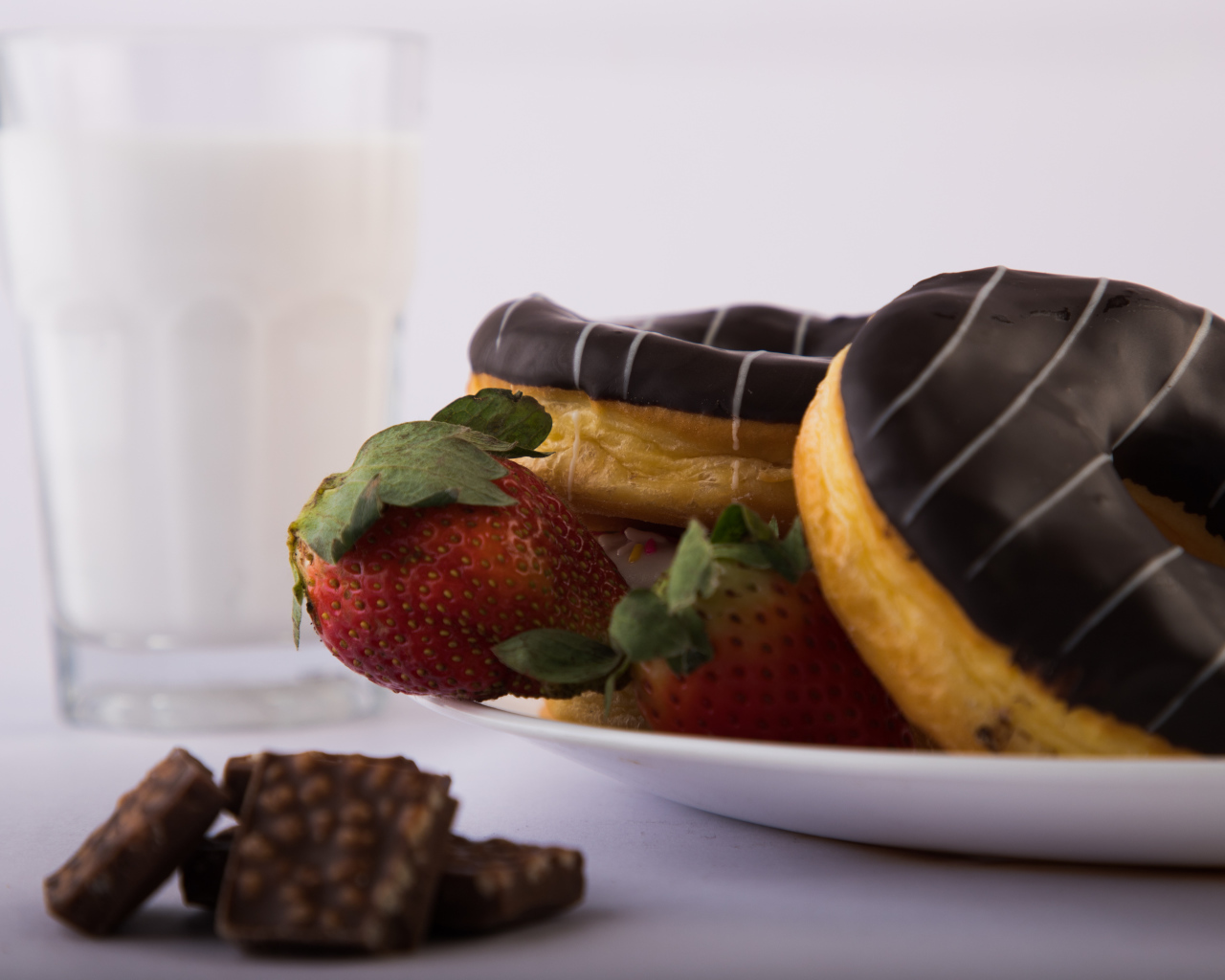 Пончики с шоколадной глазурью на тарелке с клубникой