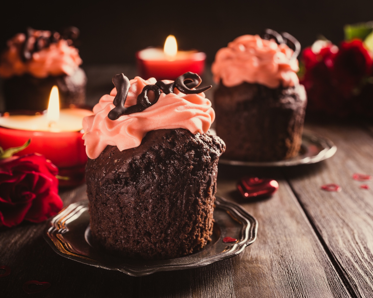 Шоколадные кексы с кремом на столе со свечами и розами