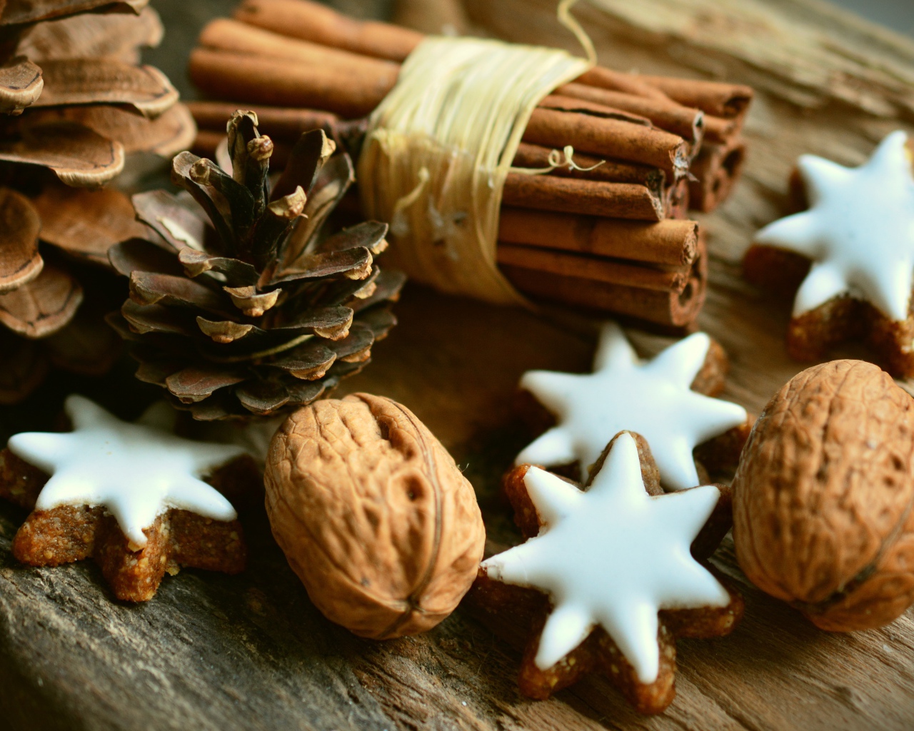 Печенье, орехи, палочки корицы и еловые шишки на деревянном столе