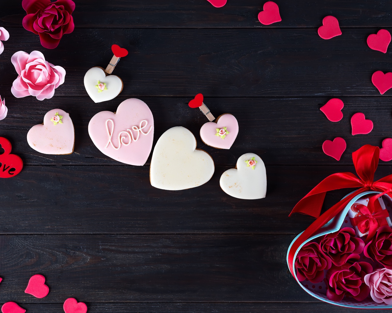 Печенье с глазурью на черной поверхности с сердечками и подарком