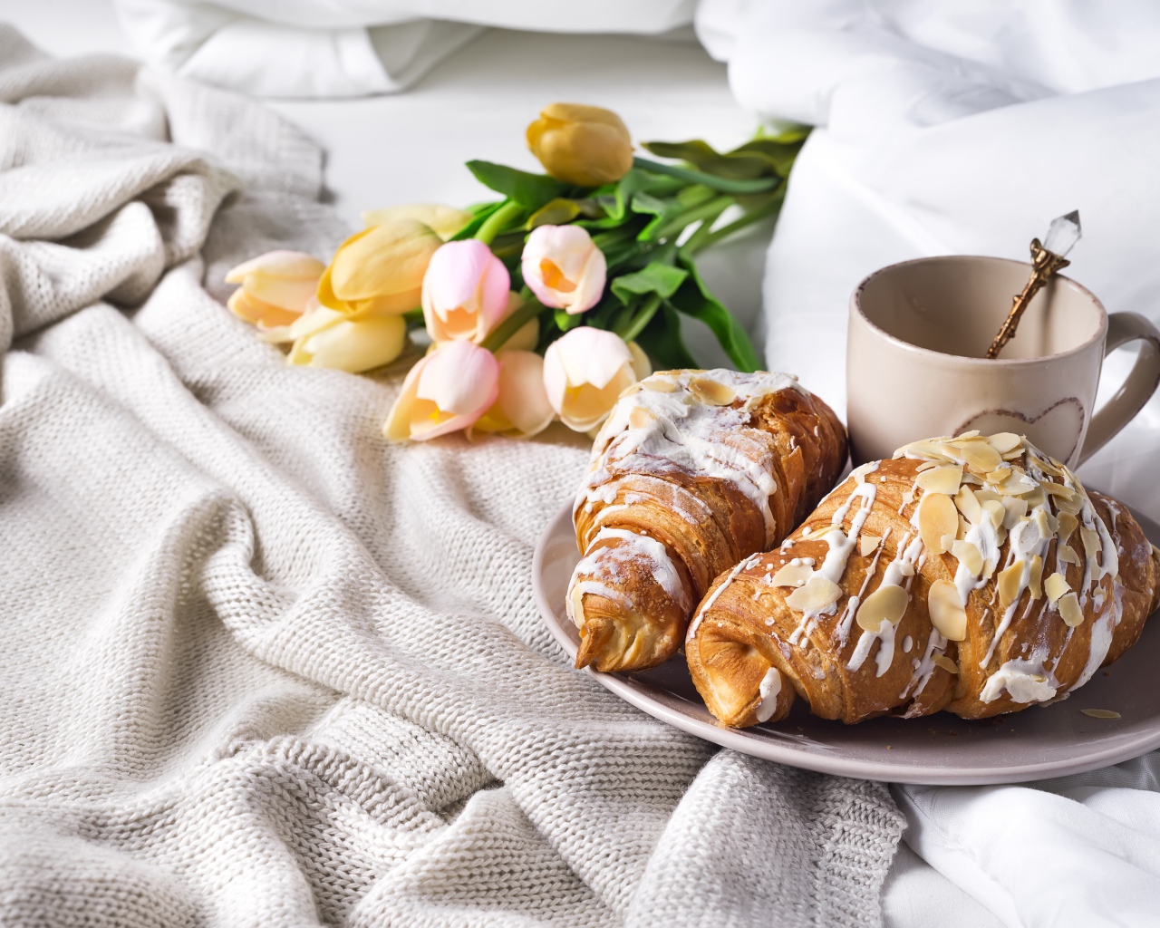 Круассаны на кровати с кофе и букетом тюльпанов