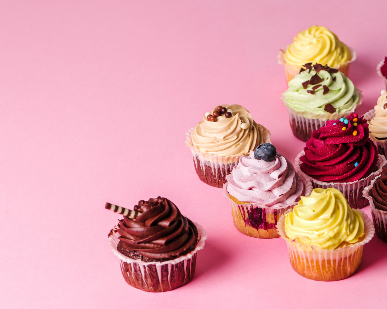 Кексы с разноцветным кремом на розовом фоне