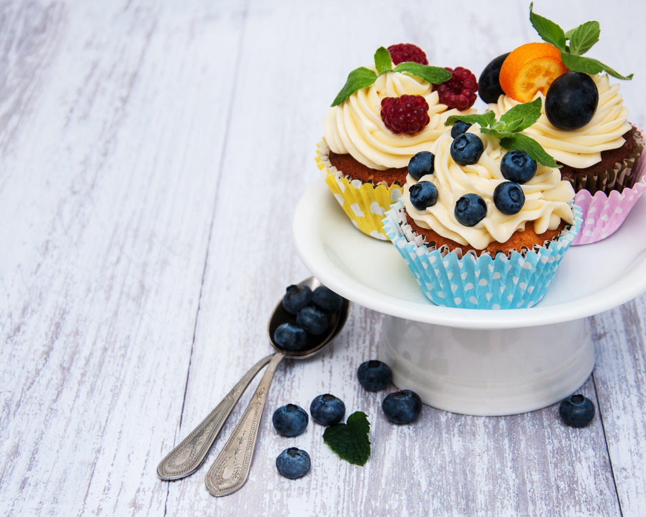 Кексы с кремом на белом блюде с ягодами