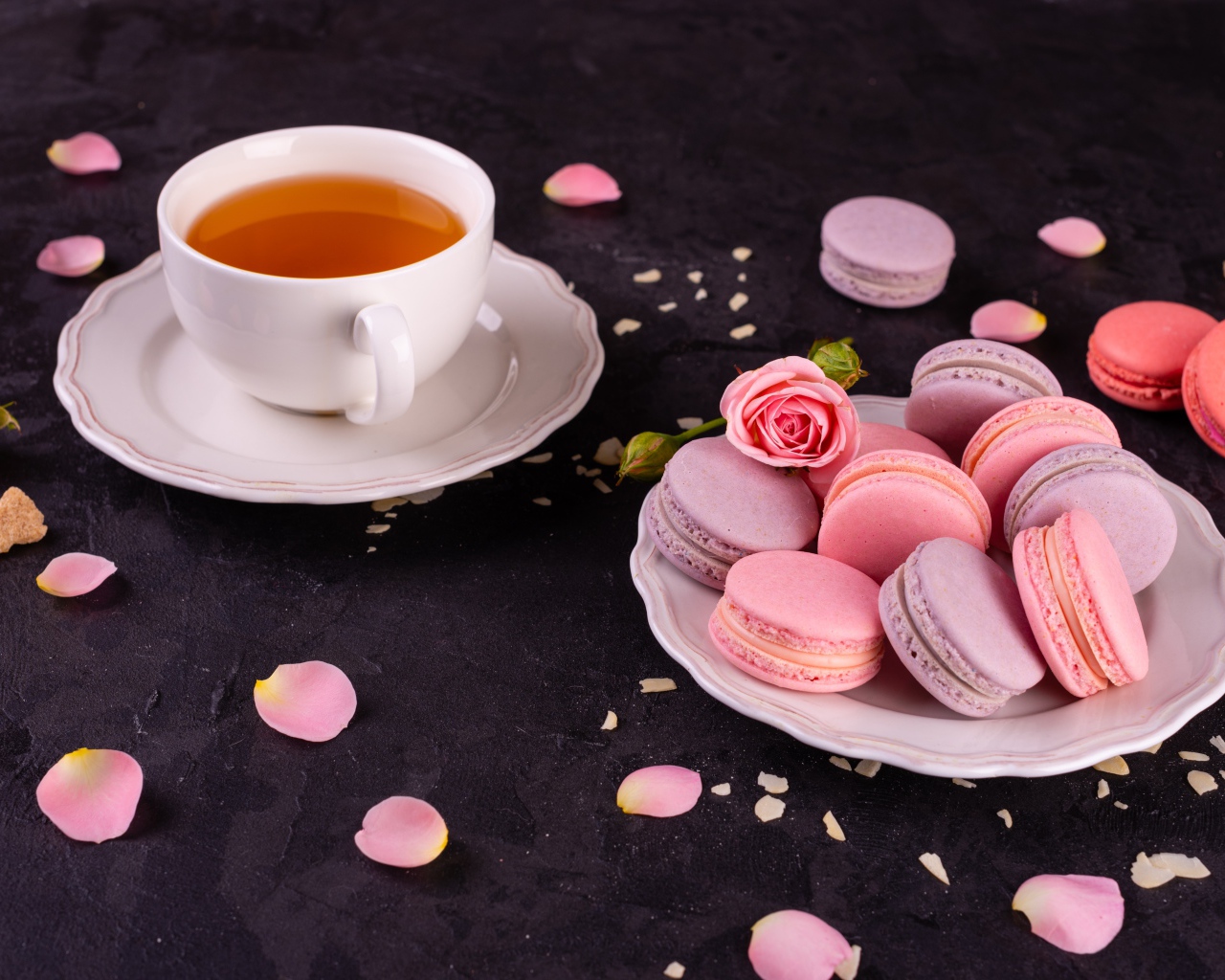 Нежный десерт макарон на столе с чашкой чая и розой