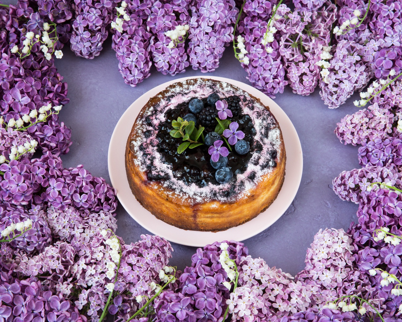 Аппетитный пирог с ягодами на столе с цветами сирени