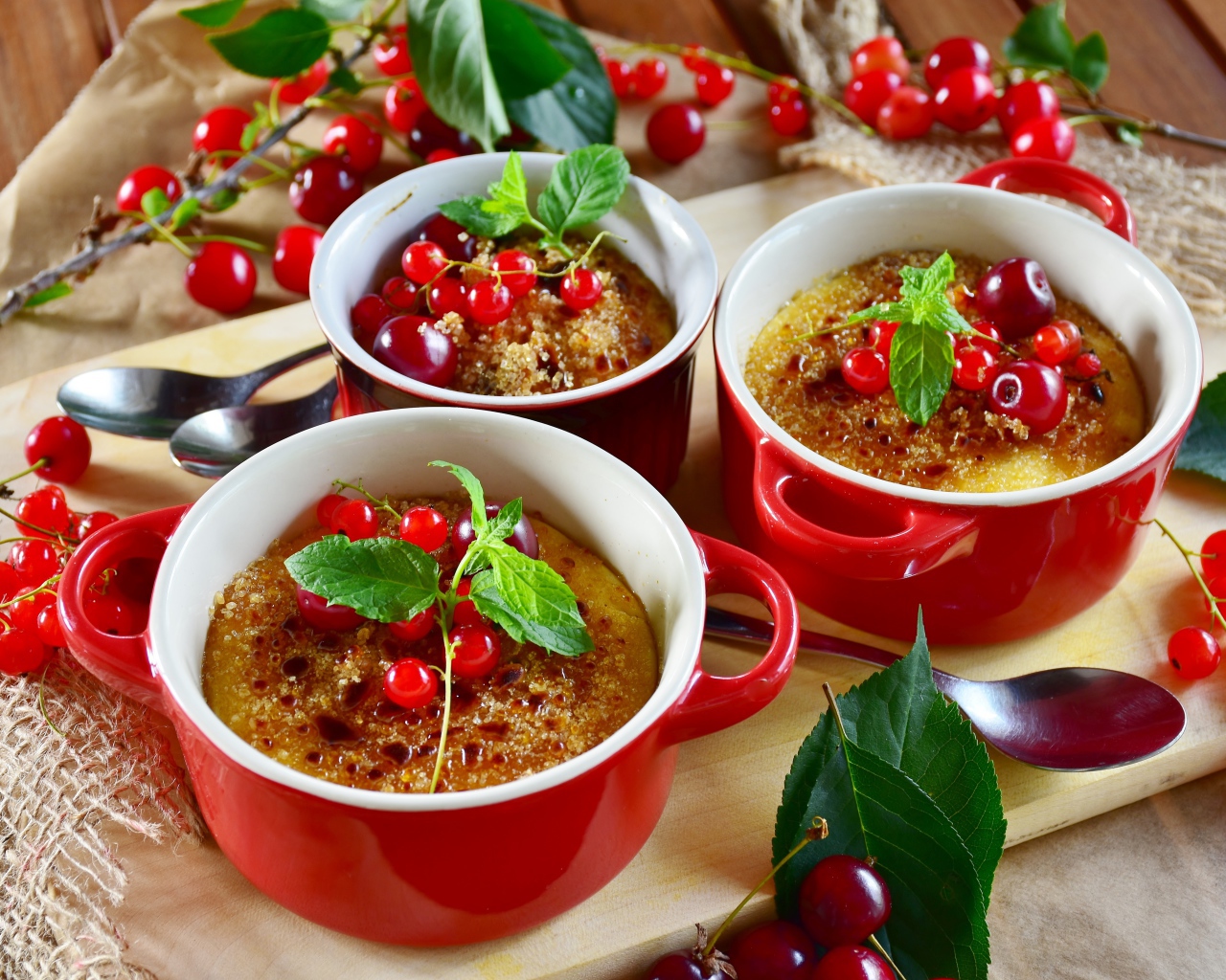 Десерт в красной посуде на столе с вишней и красной смородиной