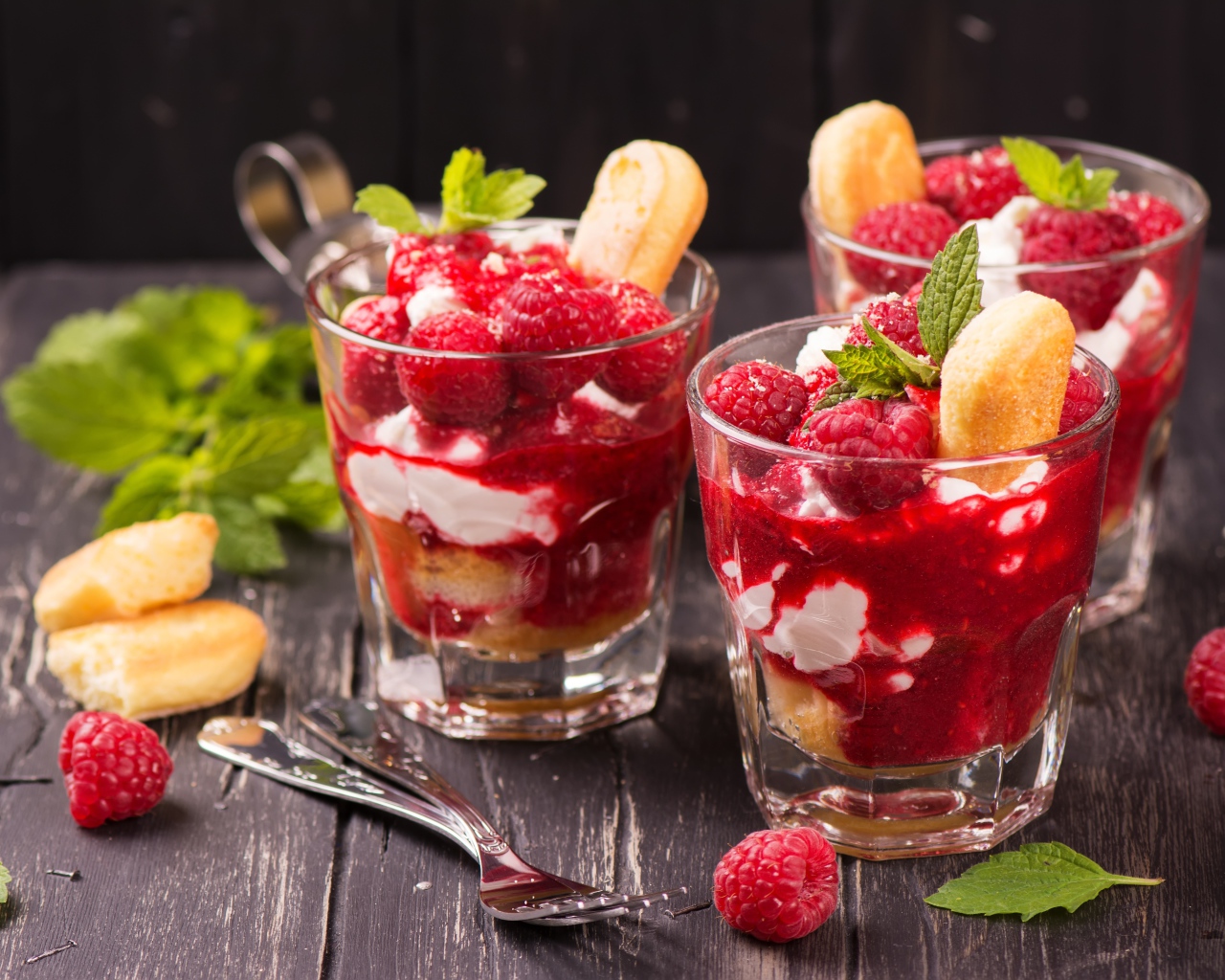 Десерт с печеньем и малиной на столе с вилками