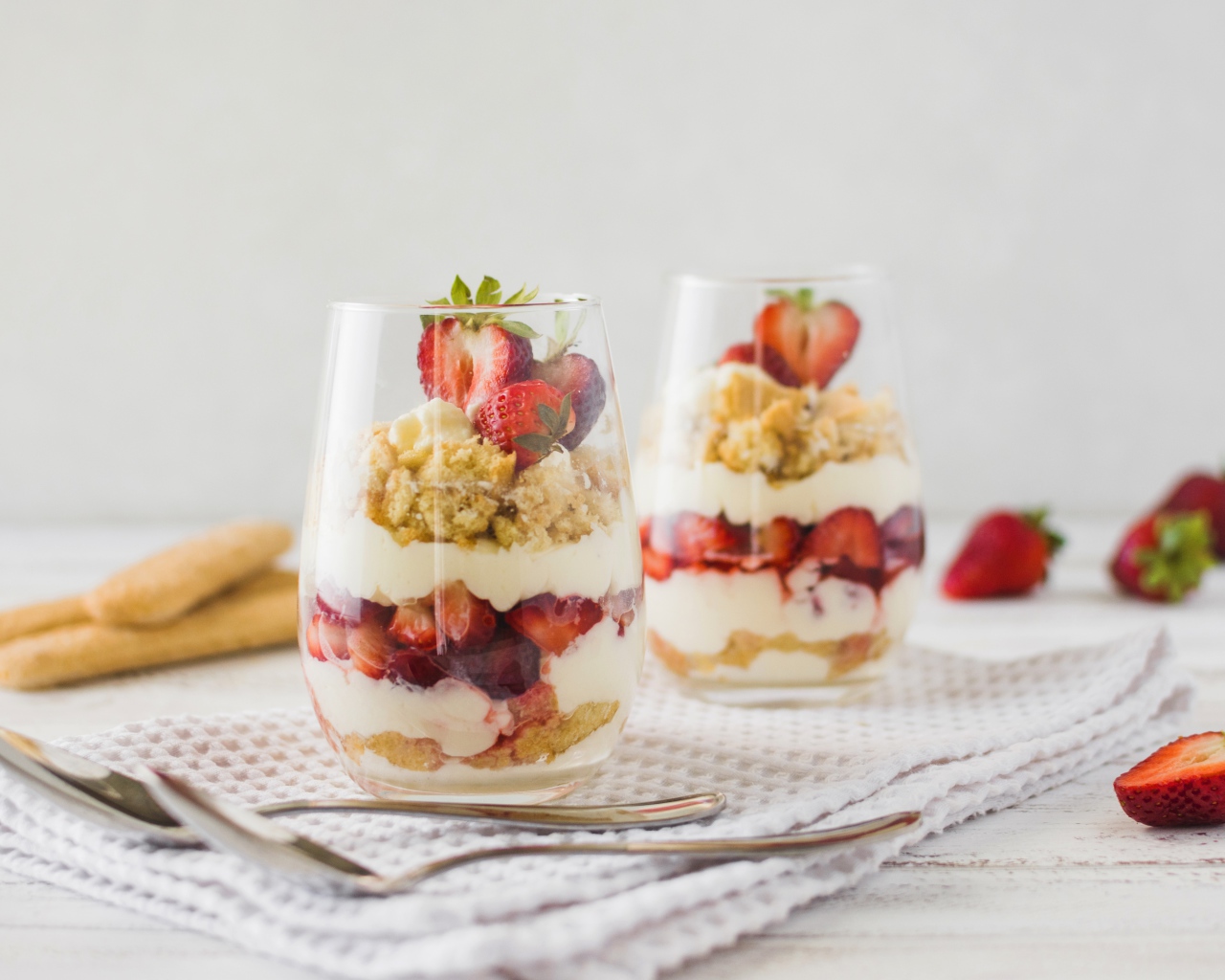 Десерт с клубникой в стеклянных стаканах на столе 