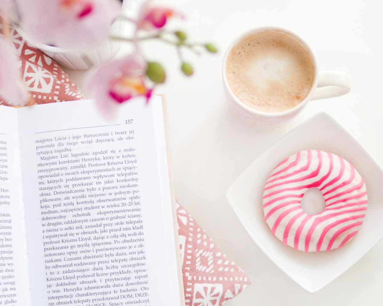 Пончик с чашкой кофе на столе с книгой