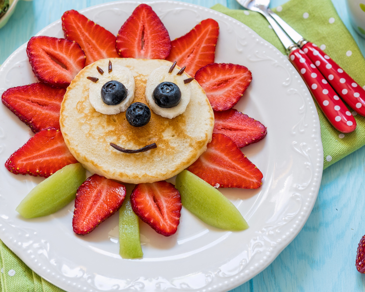 Цветок из клубники, оладьей и киви  на белой тарелке