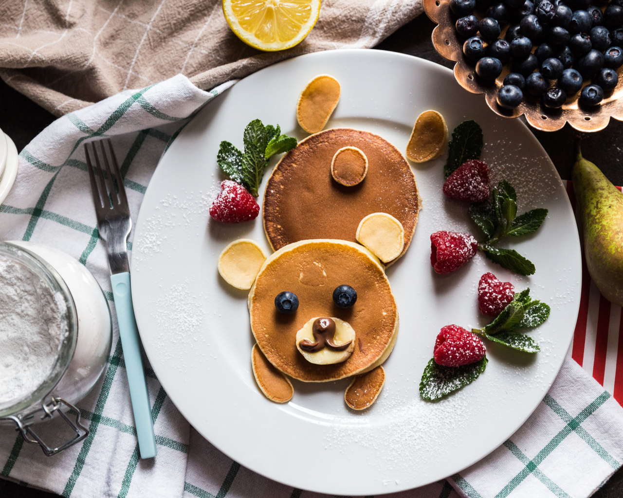 Медведь из оладьев на тарелке с малиной и сахарной пудрой