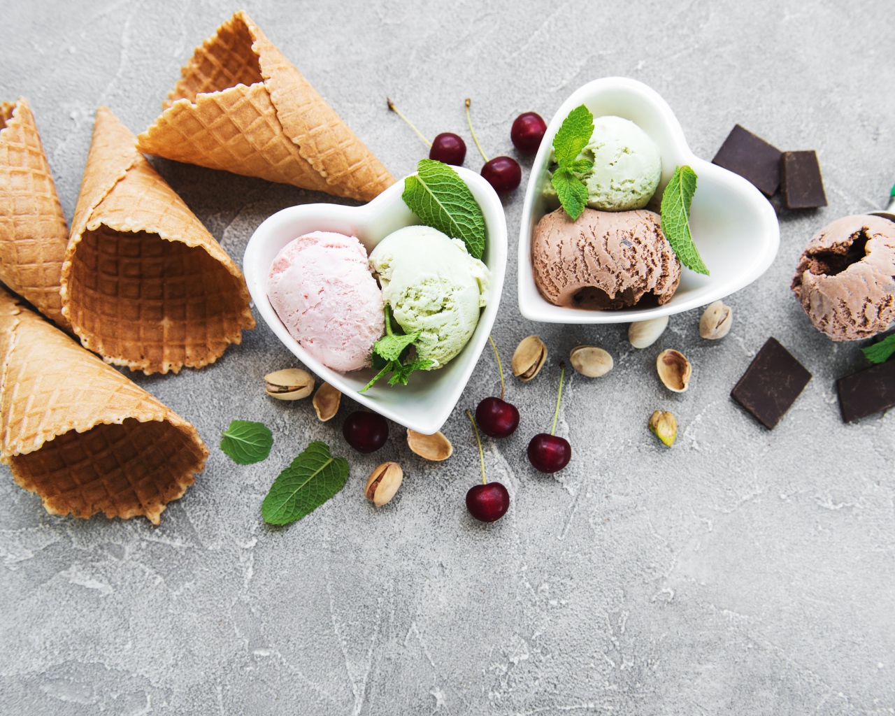 Мороженое на столе с вафельными рожками, шоколадом, вишней  и фисташками