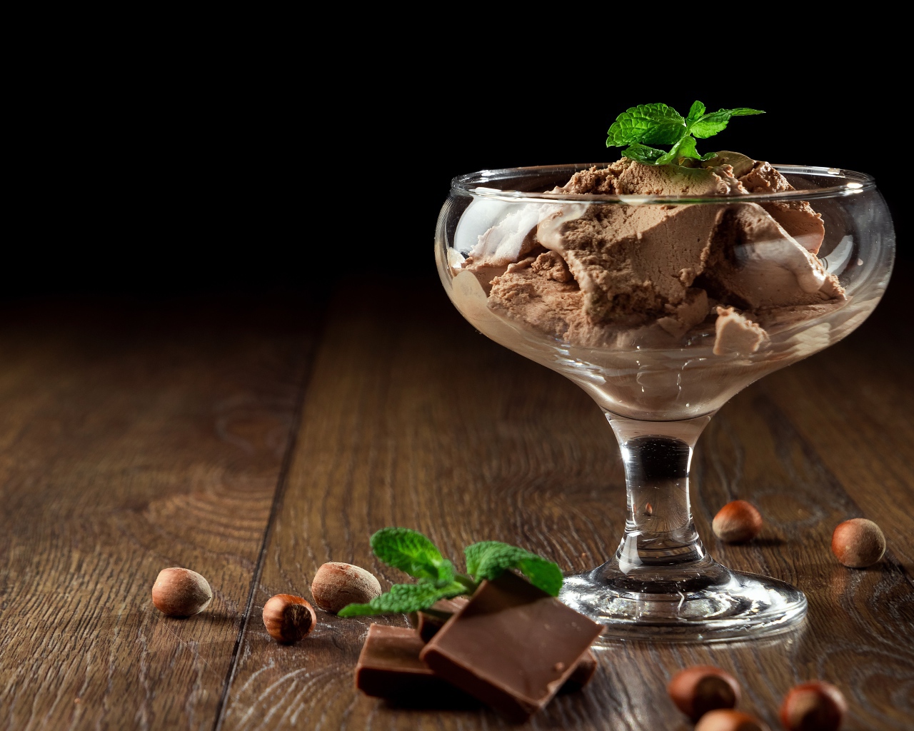 Кофейное мороженое в креманке на столе с шоколадом и орехами