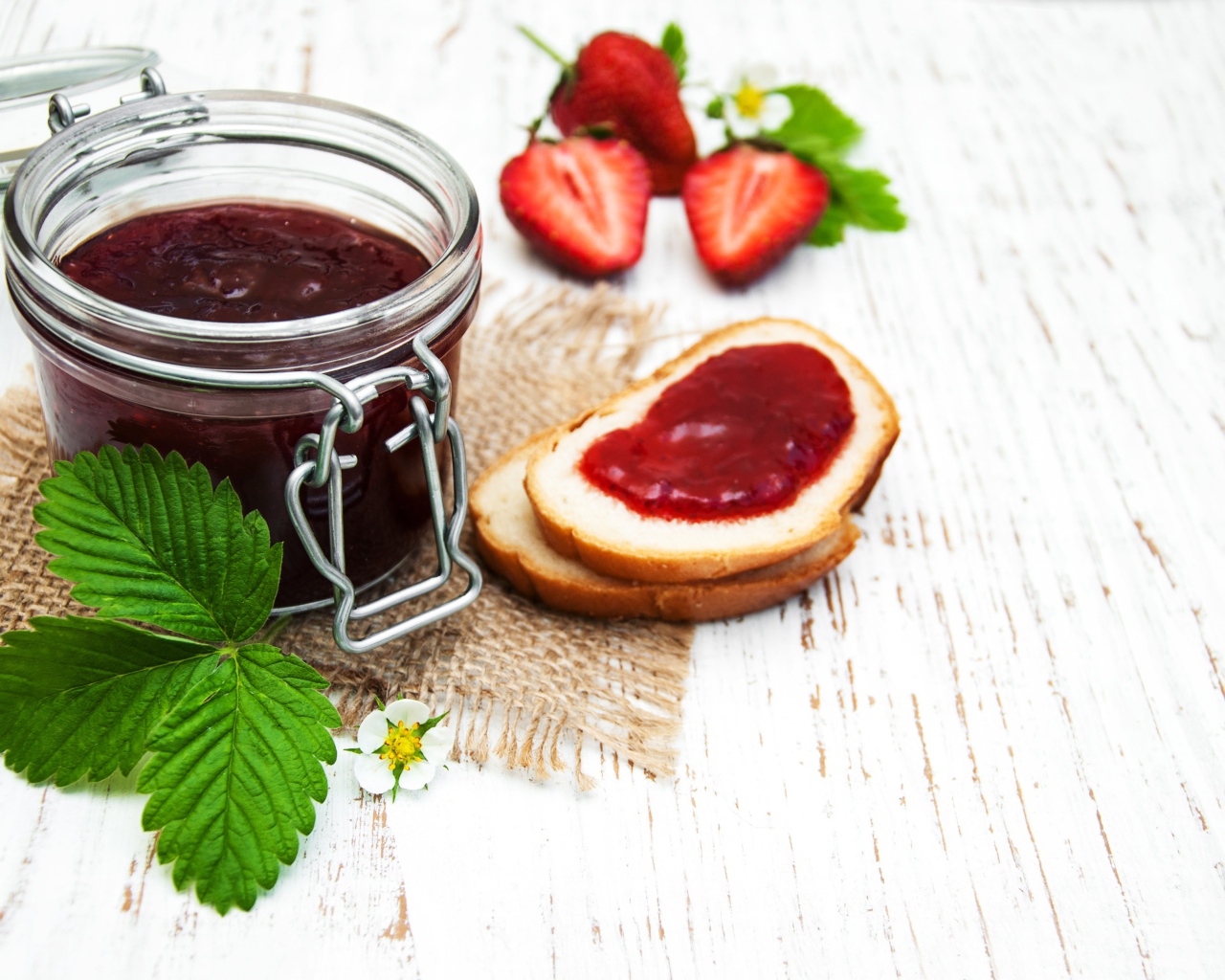 Банка клубничного джема на столе с батоном