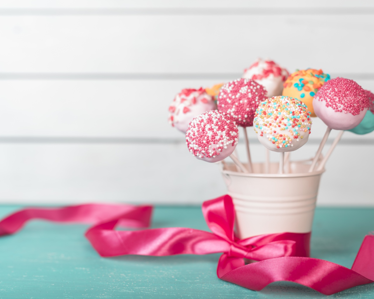 Леденцы в стакане на столе с розовым бантом из ленты