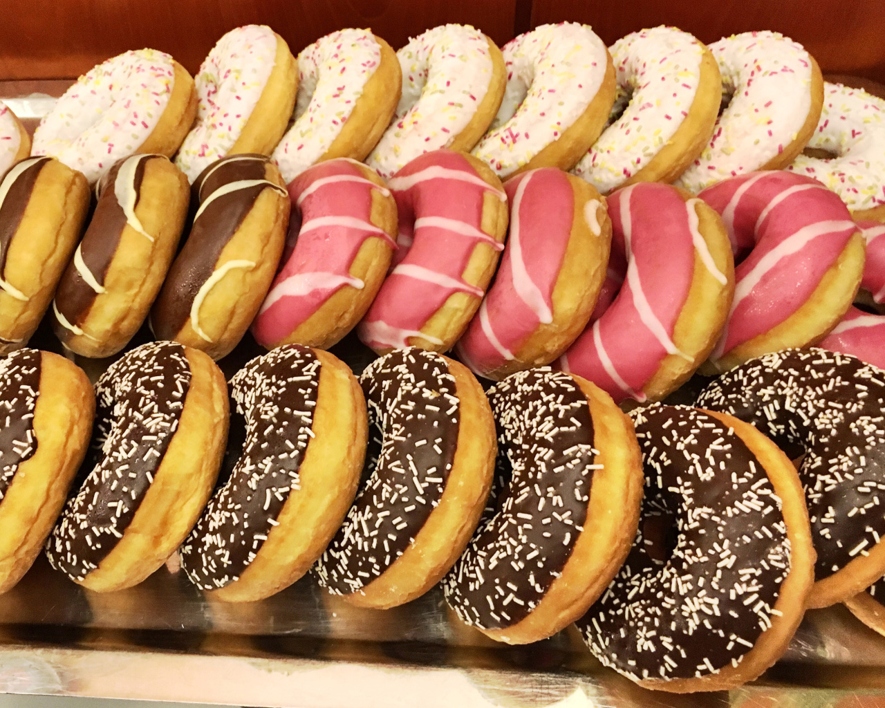 Много вкусных сладких пончиков с глазурью на столе 