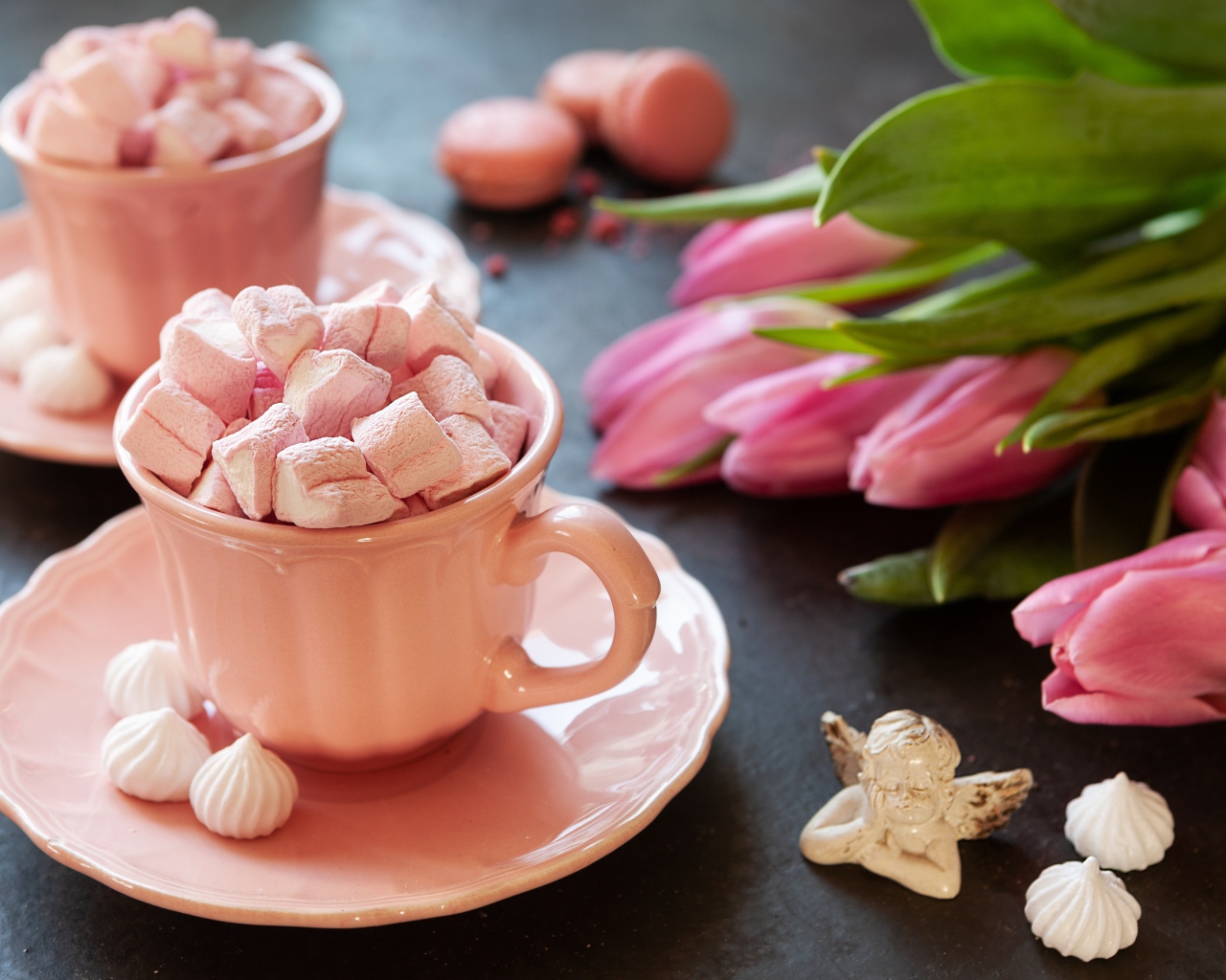 Маршмеллоу в розовой чашке на столе с букетом тюльпанов