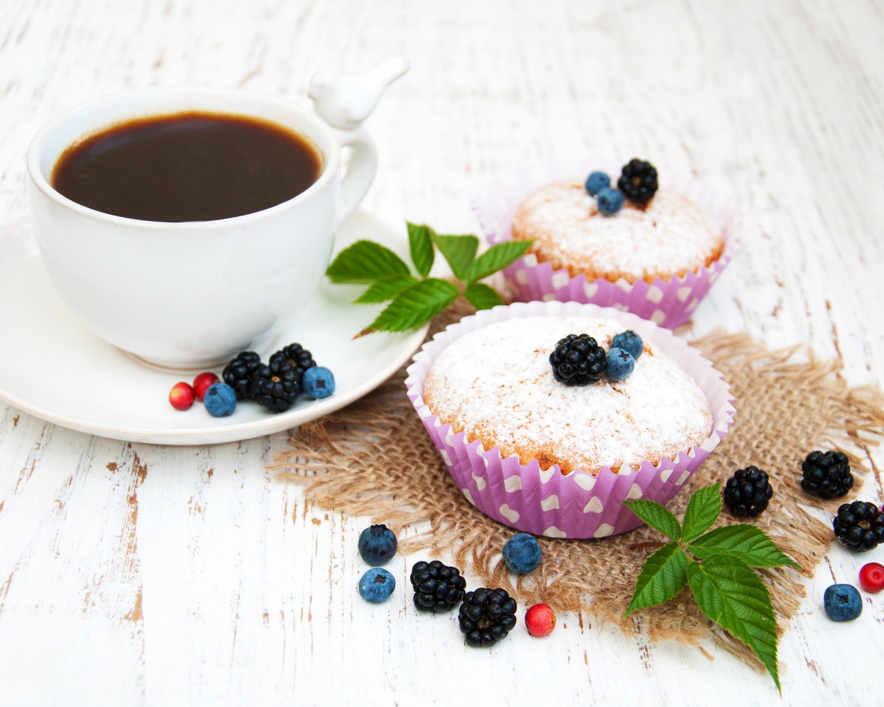 Кексы с сахарной пудрой и ягодами на столе с какао