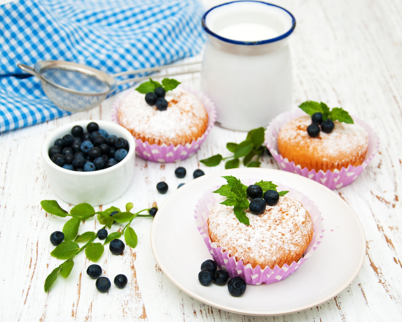 Кексы с сахарной пудрой на столе с молоком и черникой