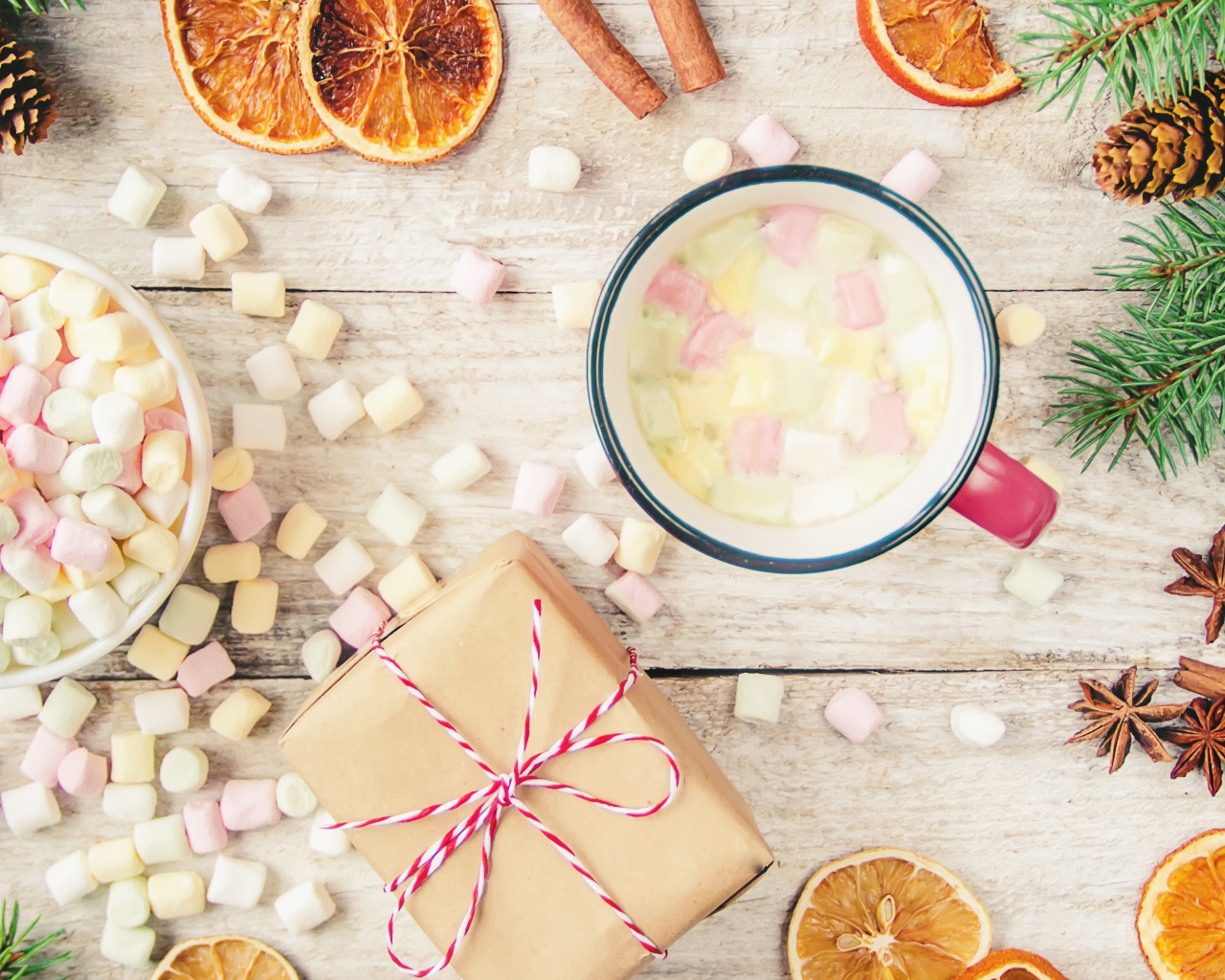 Кружка горячего напитка на столе с маршмеллоу, пряностями и подарком