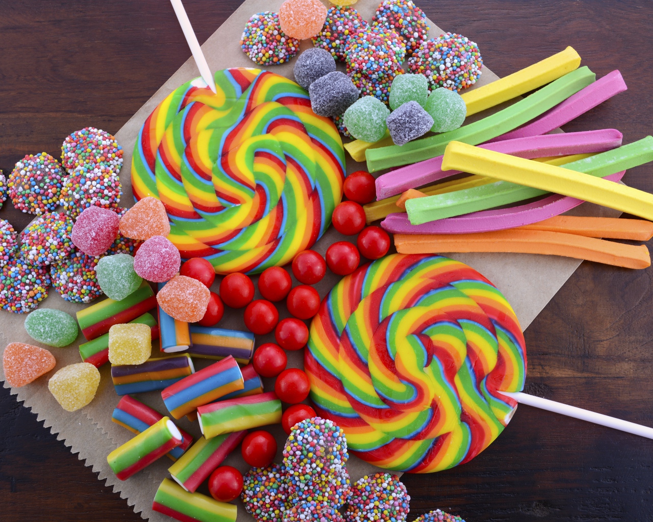 Разноцветные желейные конфеты, мармелад и леденцы на палочке на столе