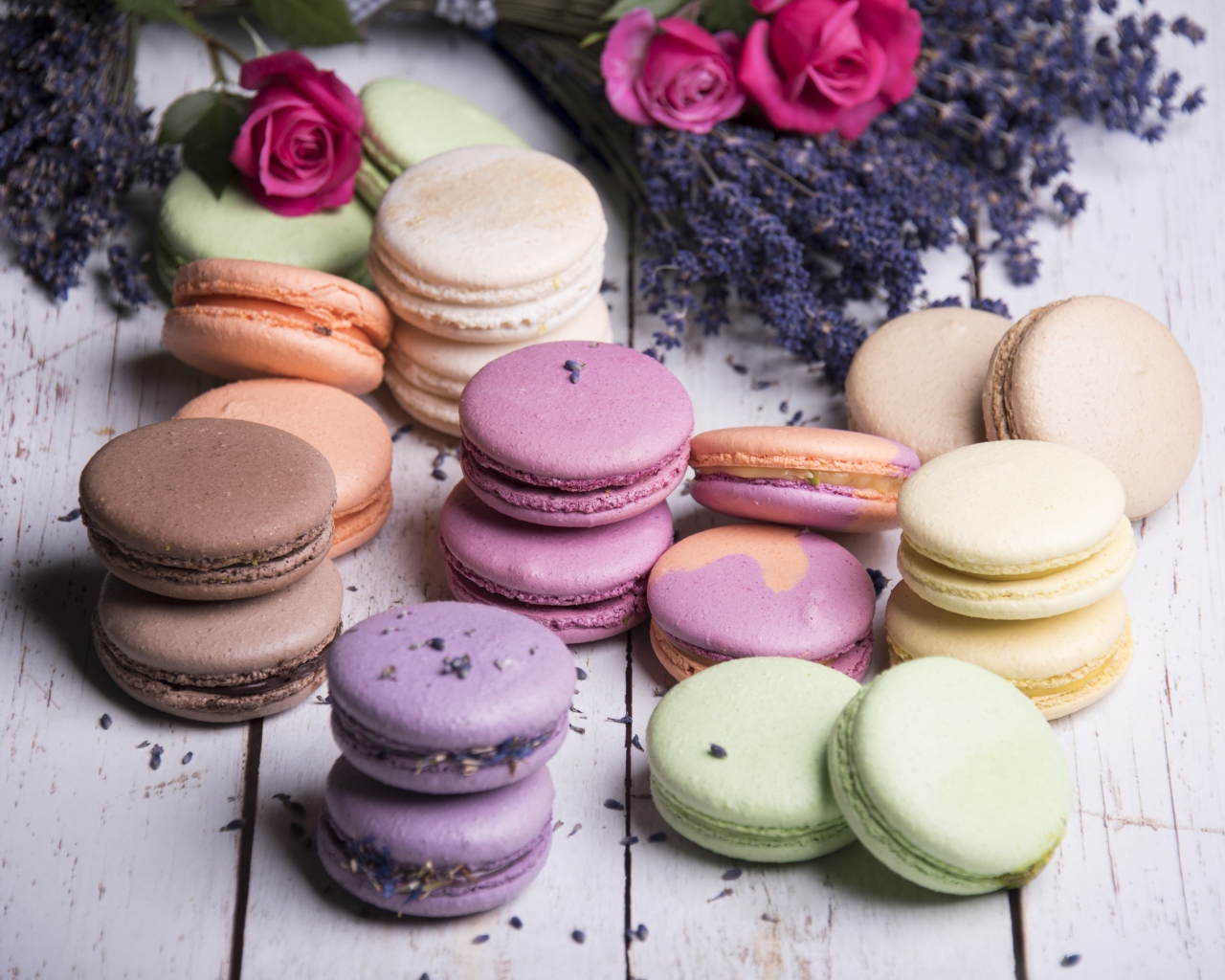 Разноцветный десерт макарон на столе с лавандой и розами