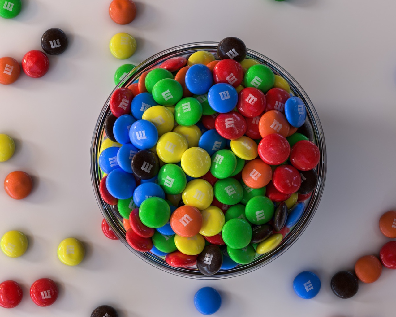 Разноцветные конфеты с миске на сером столе