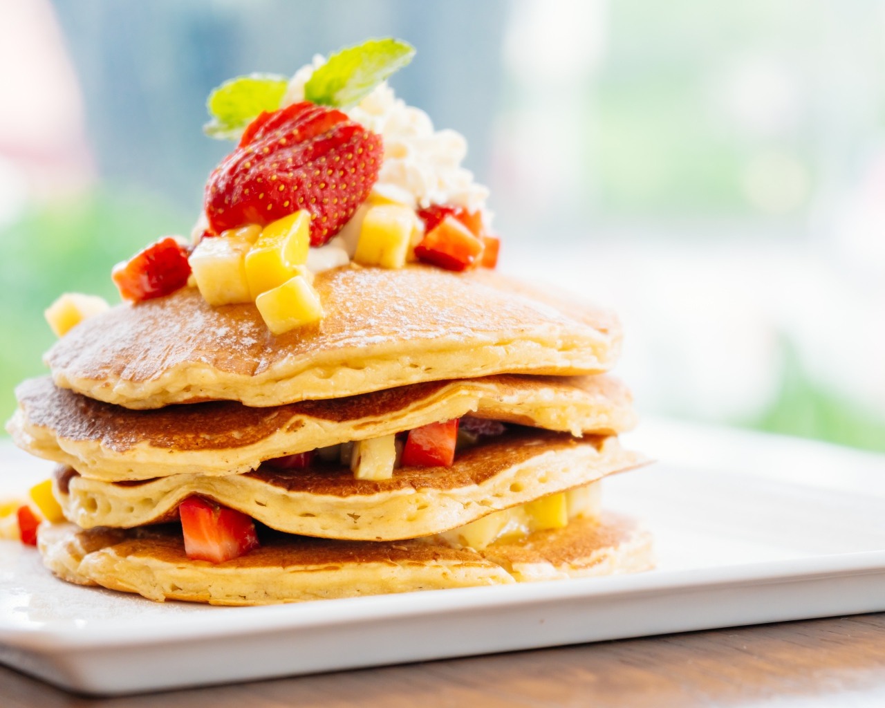 Оладьи с сахарной пудрой, сливками и кусочками клубники и ананаса