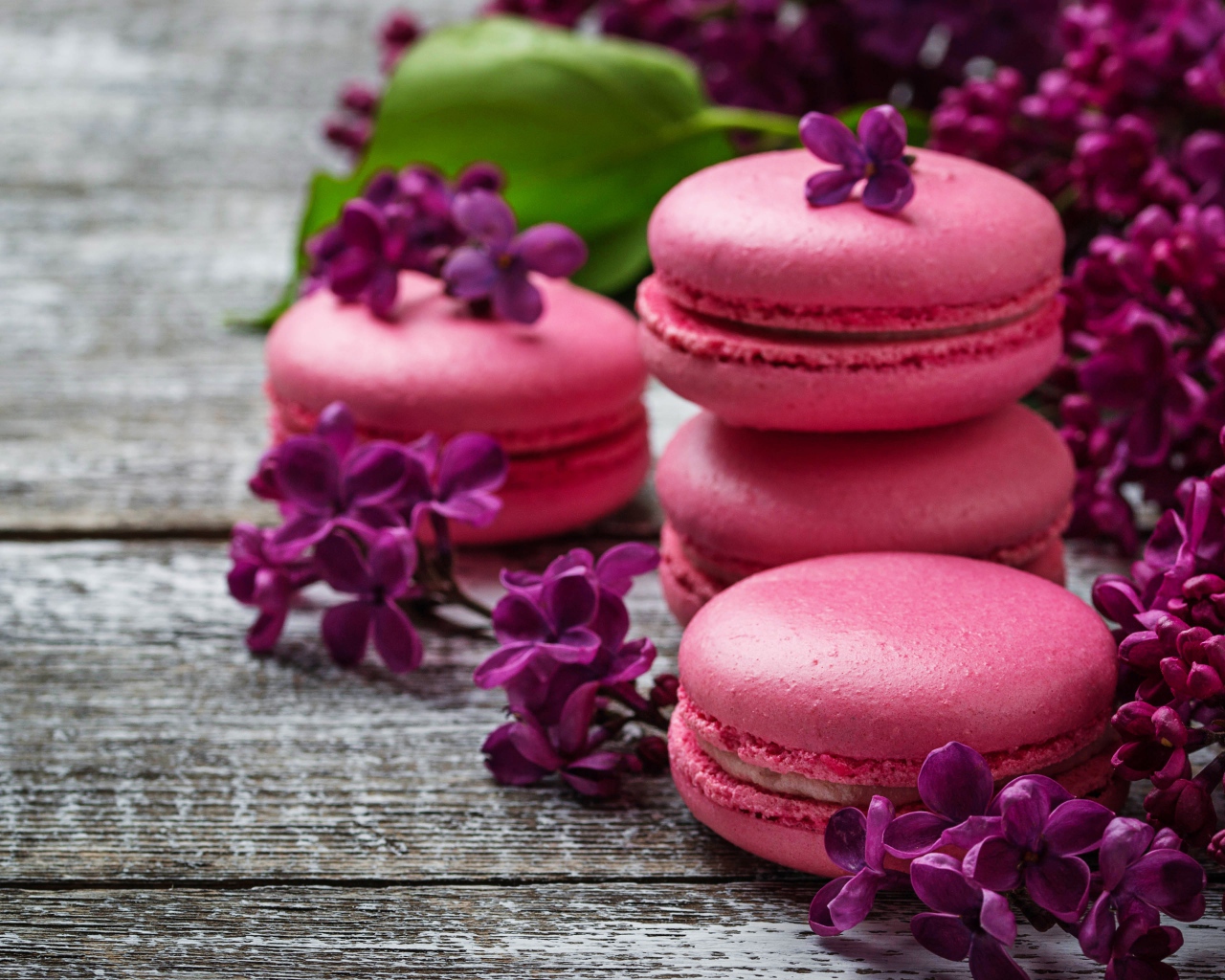 Розовый десерт макарон на столе с сиренью