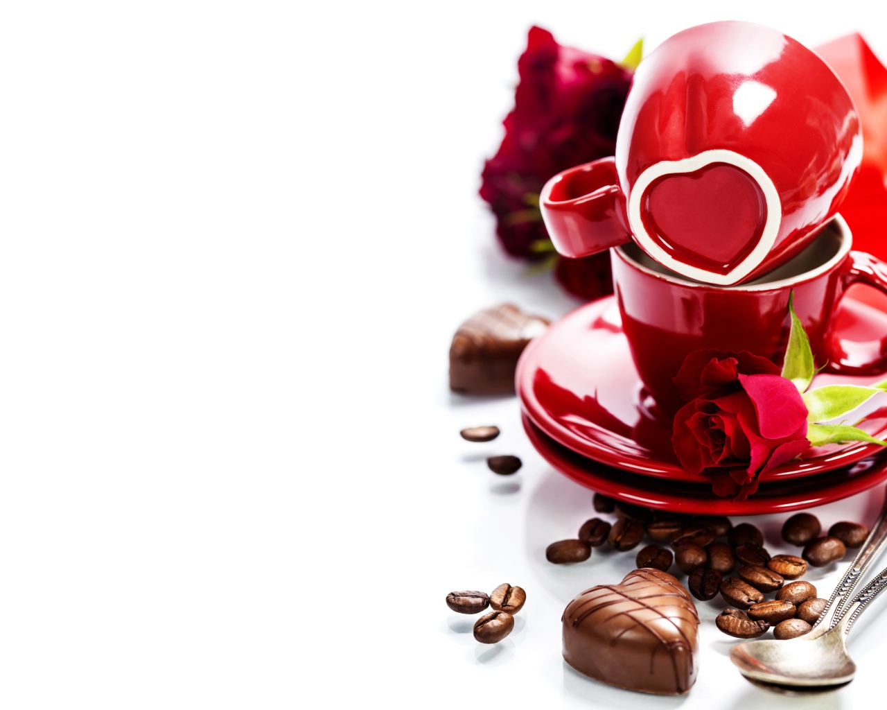 Красные чашки на белом фоне с шоколадными конфетами и кофейными зернами