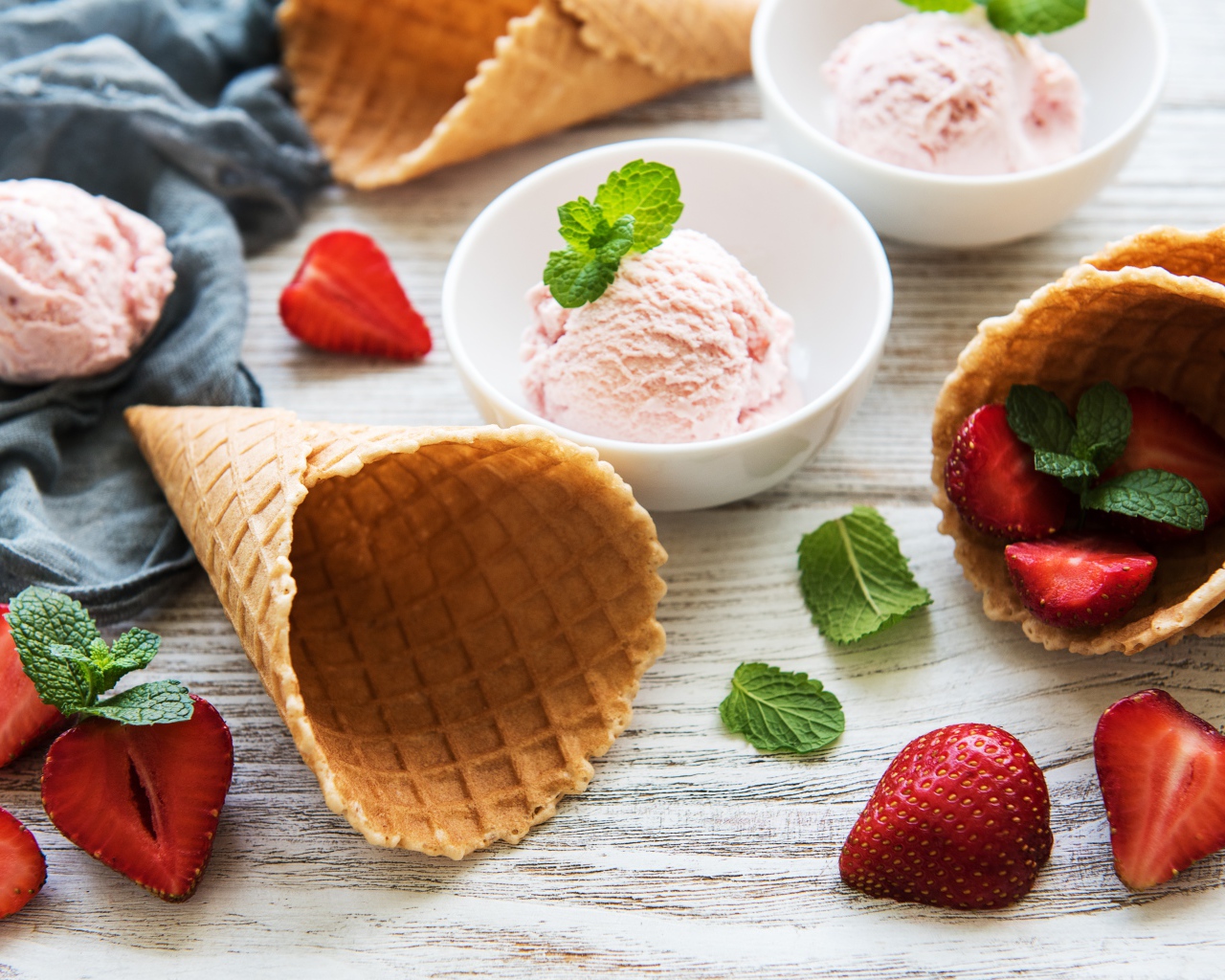 Клубничное мороженое на столе с рожками и клубникой