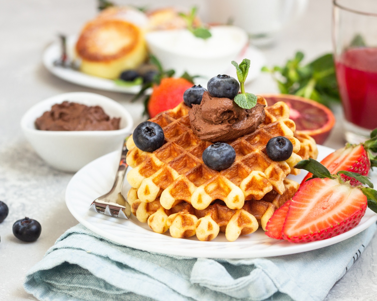Сладкая вафля с шоколадом, ягодами черники и клубники на тарелке