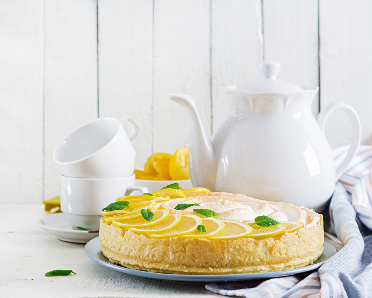 Вкусный песочный пирог с лимоном на столе с чашками и чайником