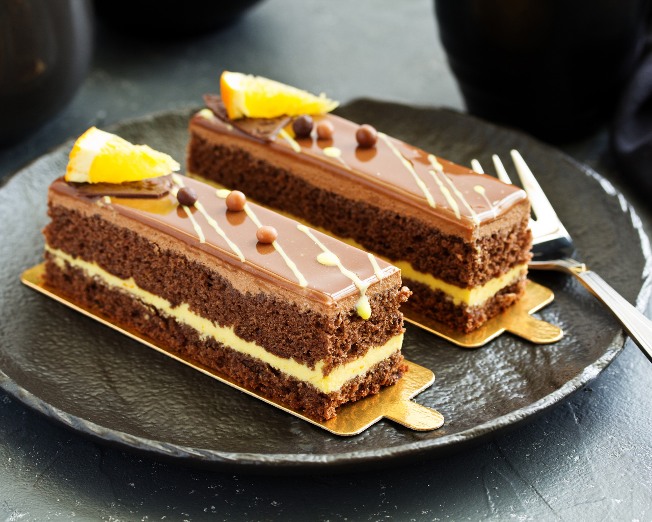 Два вкусных шоколадных пирожный на большой тарелке с вилкой