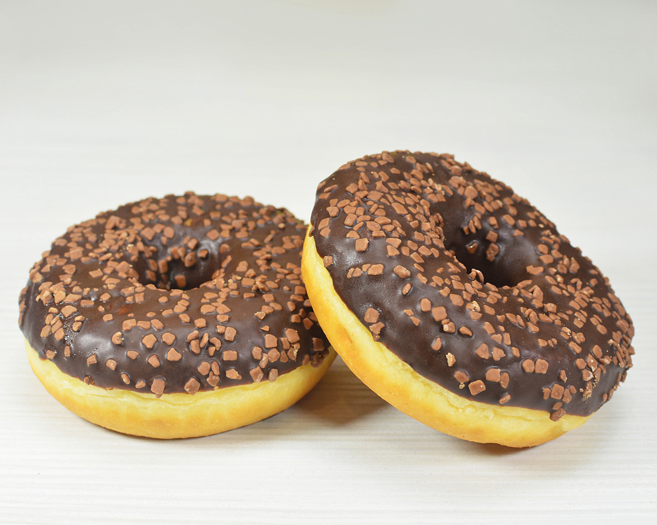 Два сладких пончика с шоколадом на сером фоне