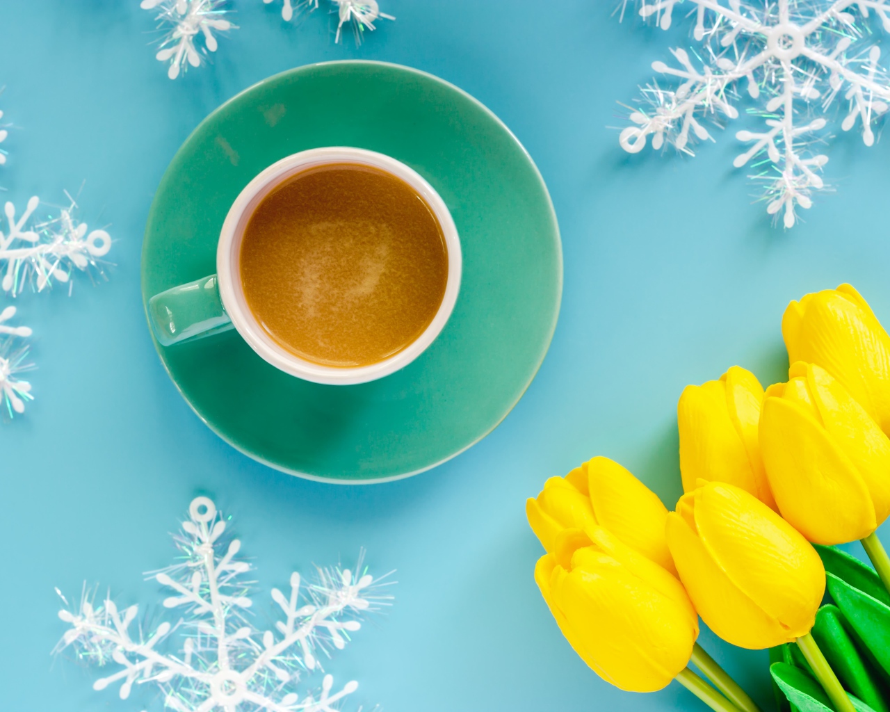 Чашка кофе на голубом фоне со снежинками и букетом желтых тюльпанов