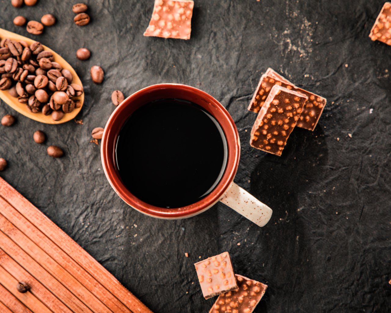 Чашка кофе на столе с кусочками шоколада и кофейными зернами