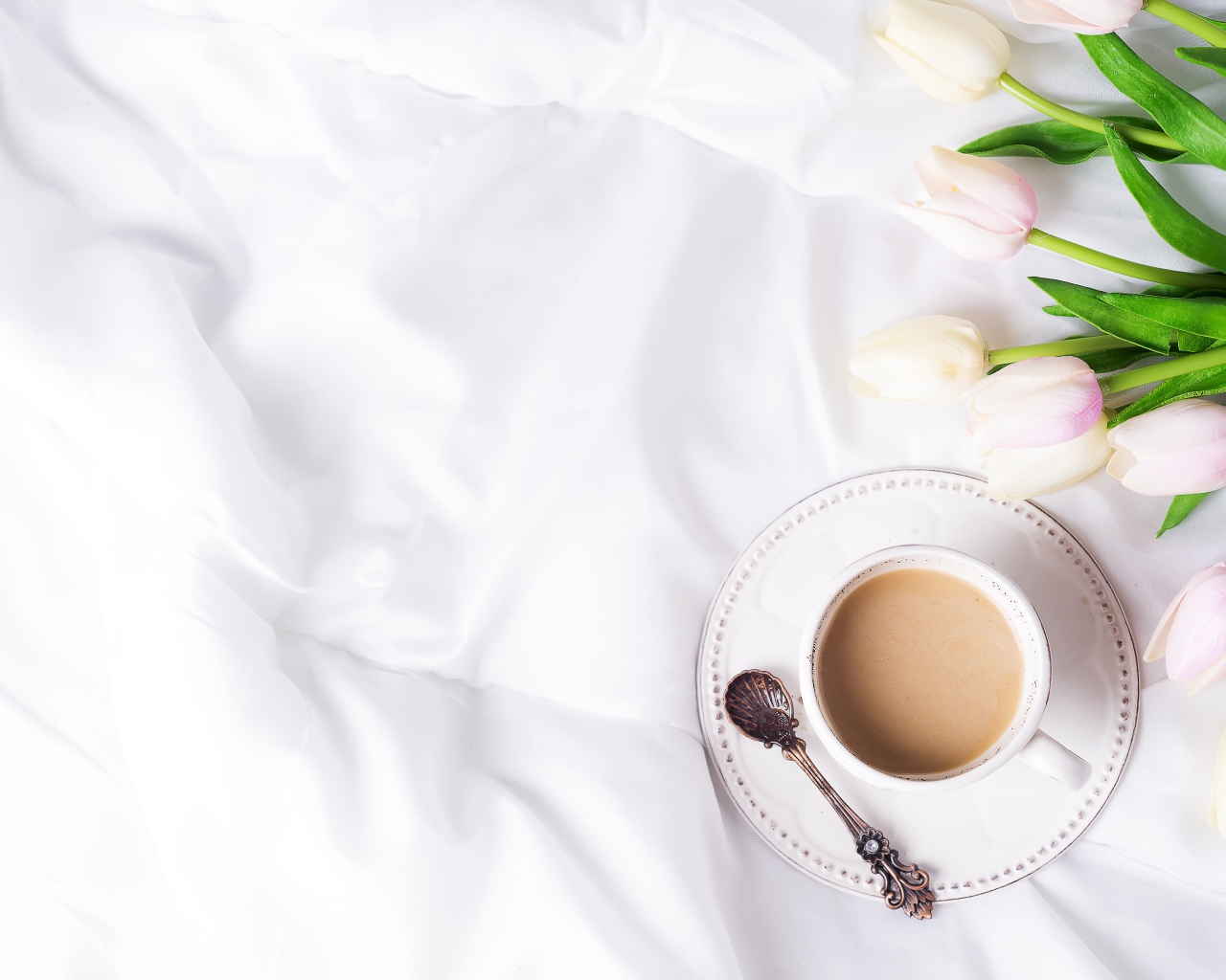Чашка кофе на белом покрывале с тюльпанами