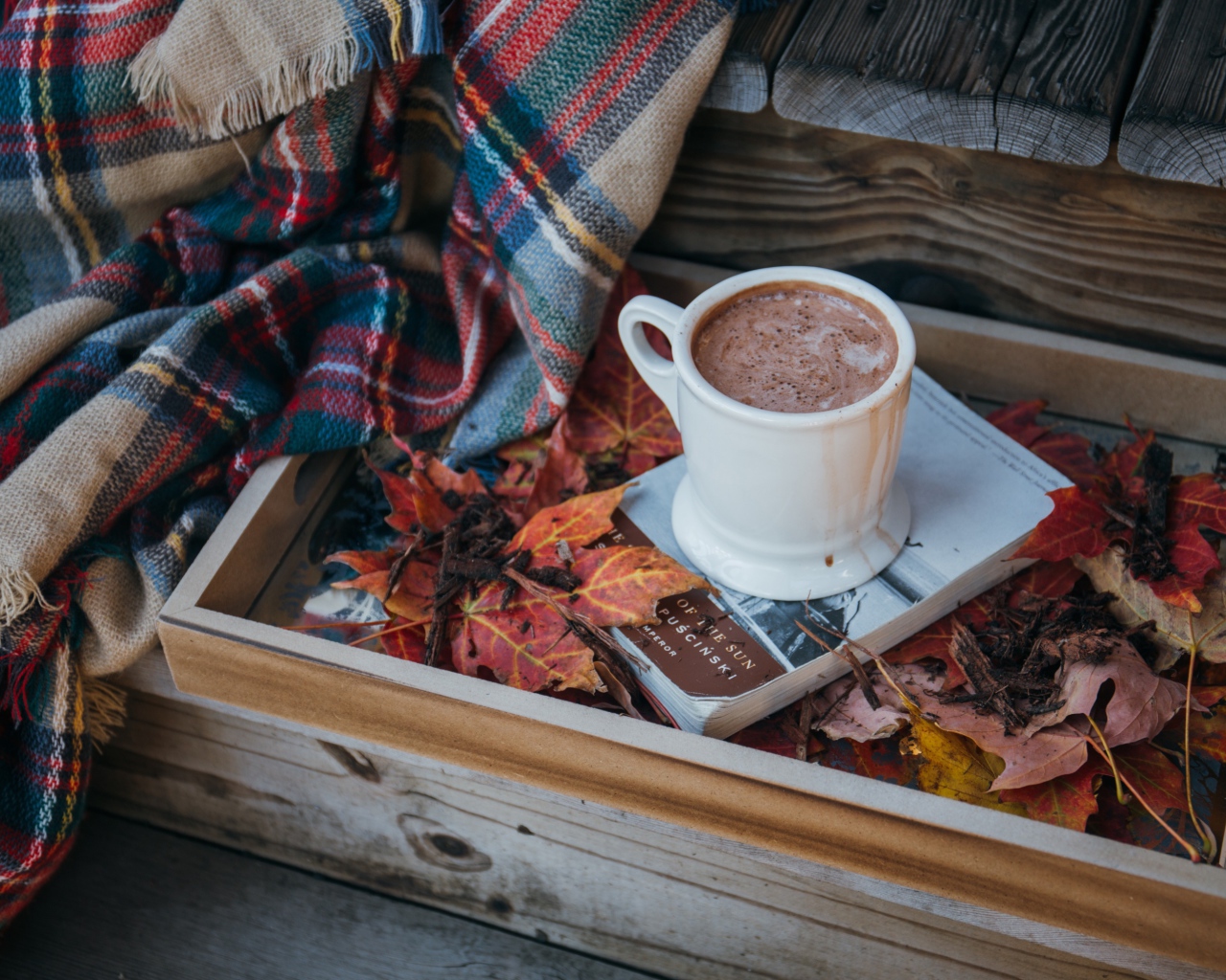 Чашка кофе стоит на книге на ступеньках с пледом