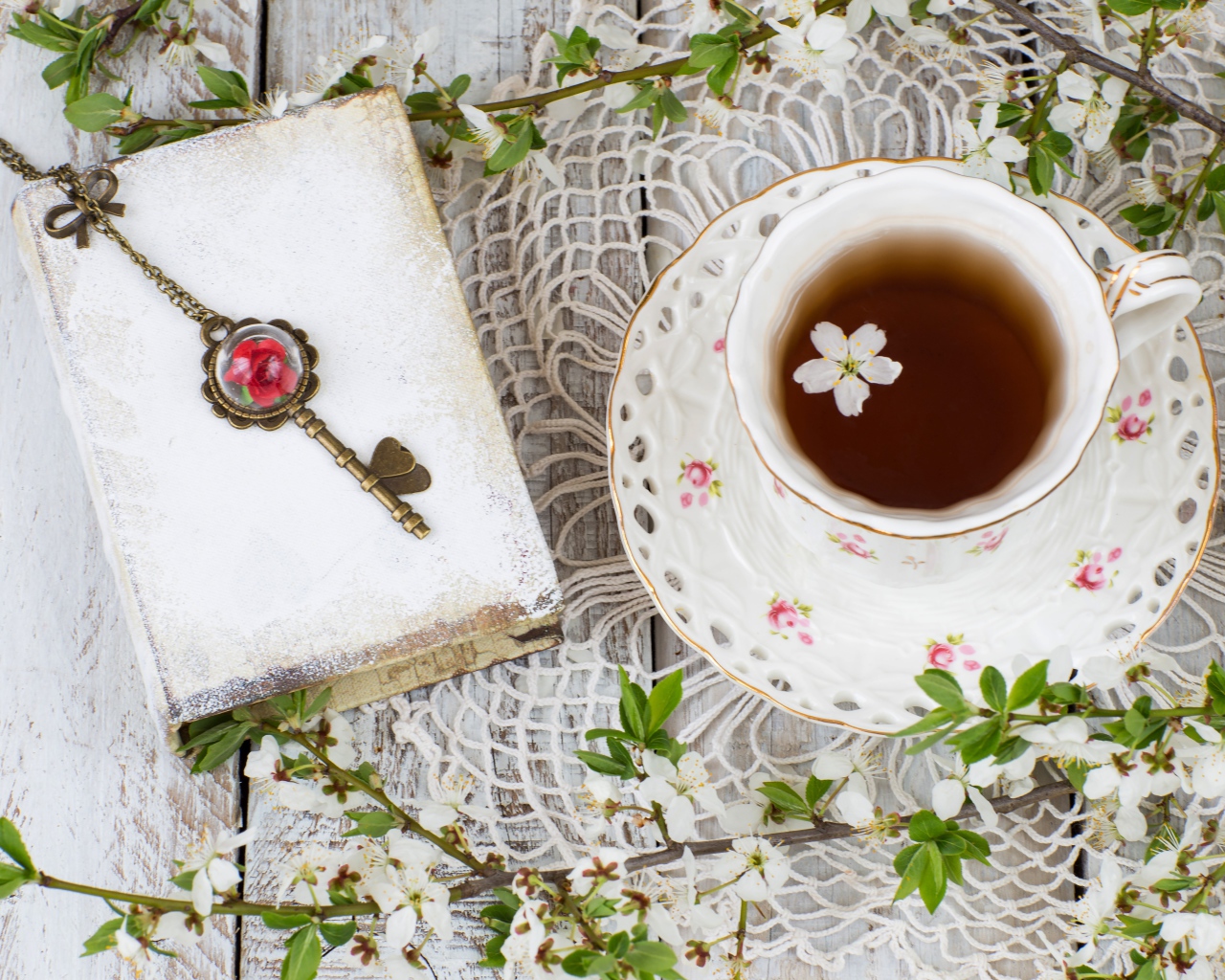 Чашка чая на столе с книгой и белыми цветами вишни 