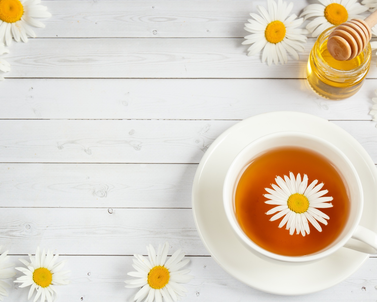 A cup of tea with chamomile on the table with honey