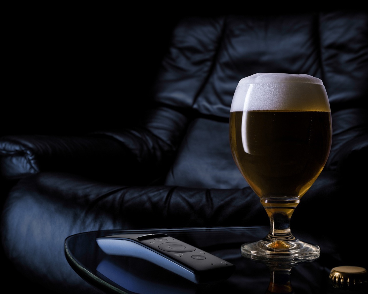 Бокал пива на фоне черного кожаного кресла