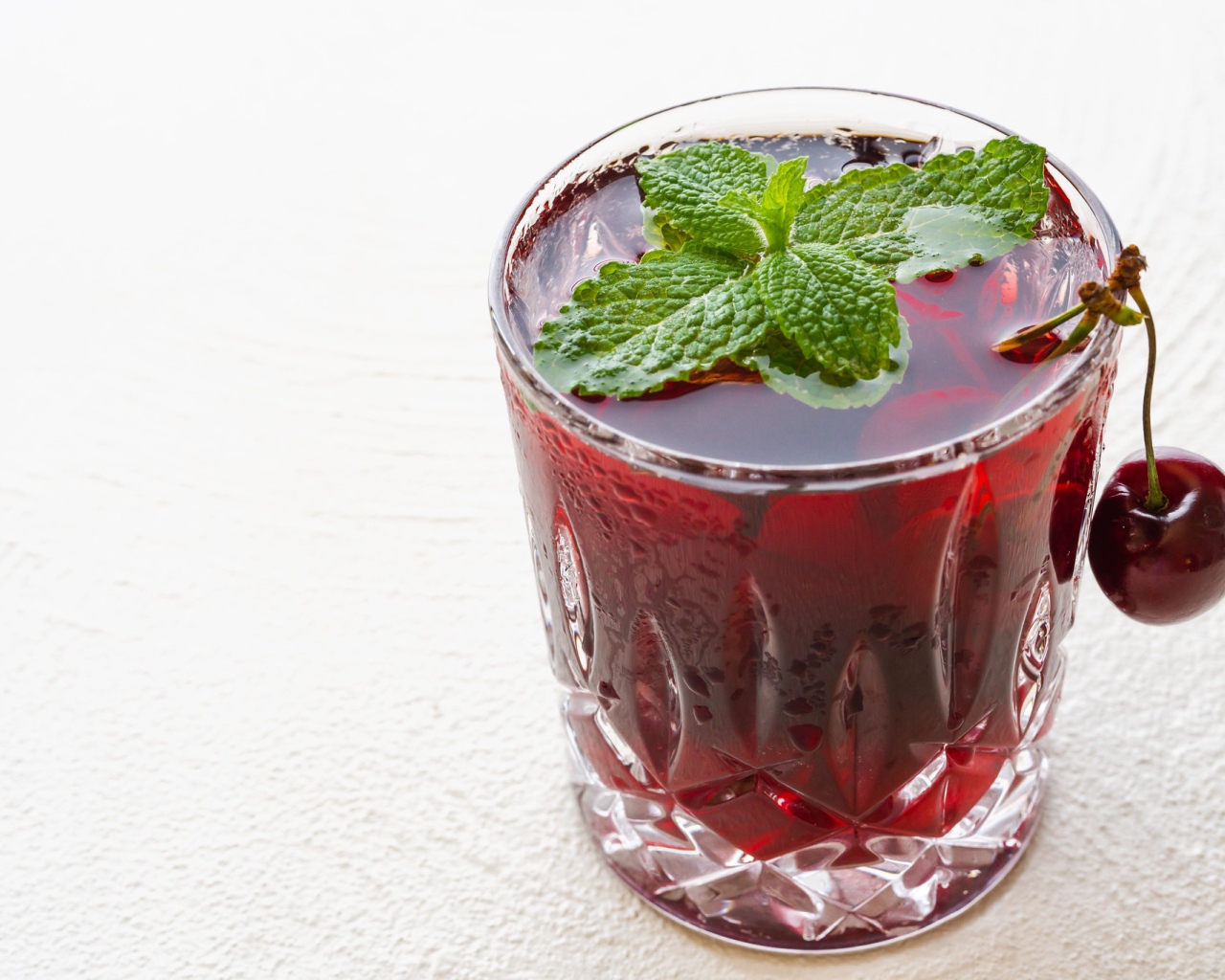 Стакан вишневого сока с мятой на белом фоне