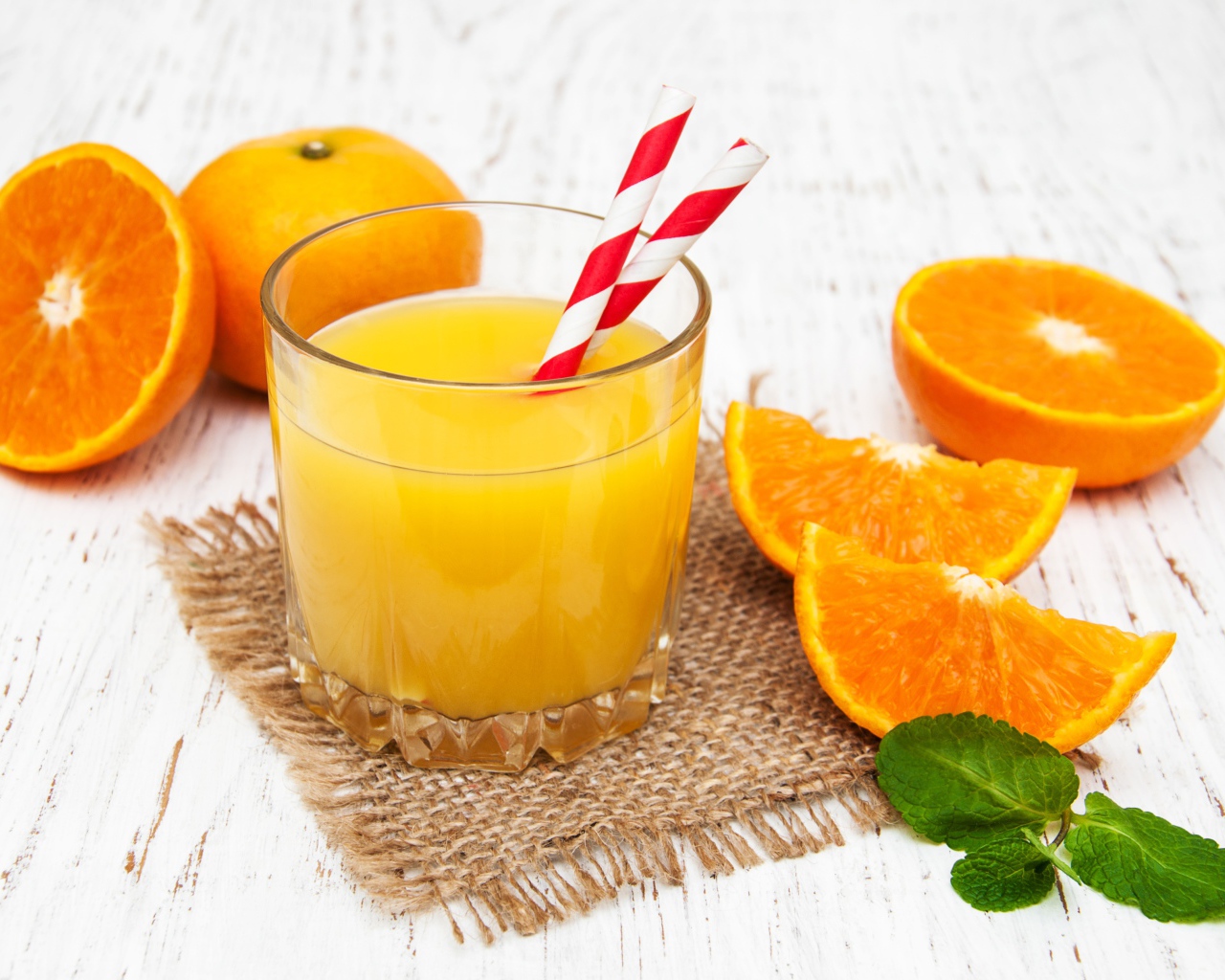 Стакан свежего сока на столе с апельсинами